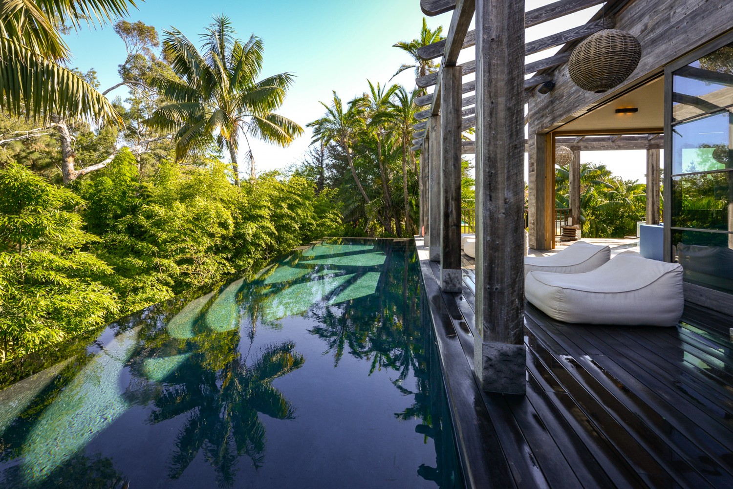 Infinity-edge pool surrounded by lush tropical landscaping and Balinese-inspired architecture at a private Malibu estate for weddings, retreats, and special events.