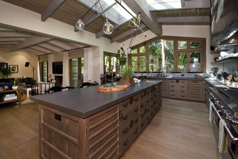 Gourmet chef's kitchen with a large island, exposed beams, and garden views at a private Malibu estate.