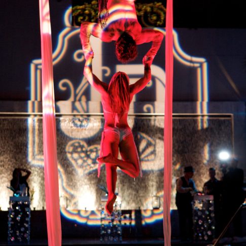 Professional acrobatic performers entertaining guests during a luxury rooftop event with elegant cabanas, custom lighting, and premium event production by Gianna & Company.