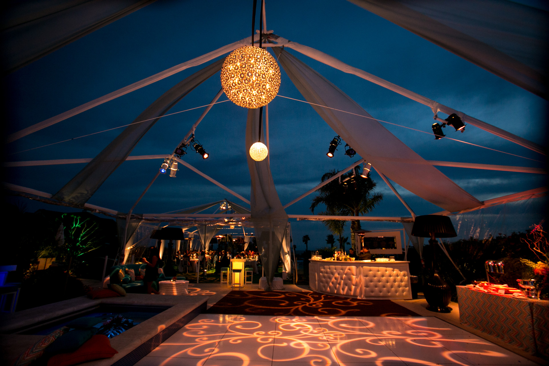 Elegant tented reception at a private estate featuring custom lighting, lounge seating, a modern bar, and luxury event design for an evening celebration.