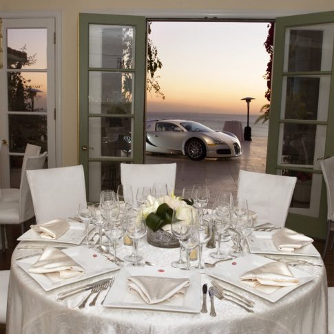 Elegant dining room overlooking the Pacific Ocean during a luxury Bugatti event at a private estate, featuring refined tablescapes and sunset views.