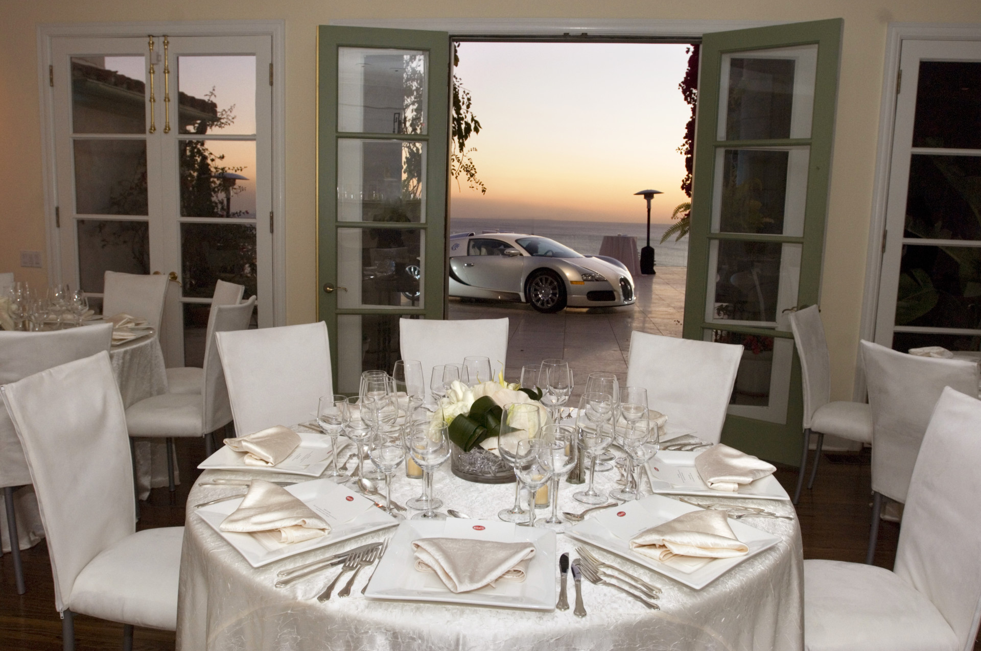 Elegant dining room overlooking the Pacific Ocean during a luxury Bugatti event at a private estate, featuring refined tablescapes and sunset views.