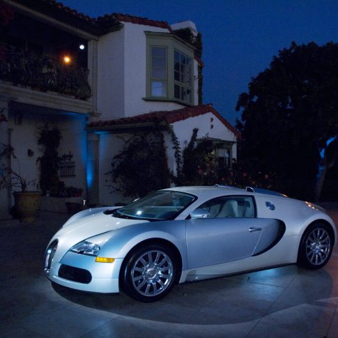 Bugatti Veyron arriving at an elegant private estate for an exclusive evening event featuring Mediterranean architecture and sophisticated event production.