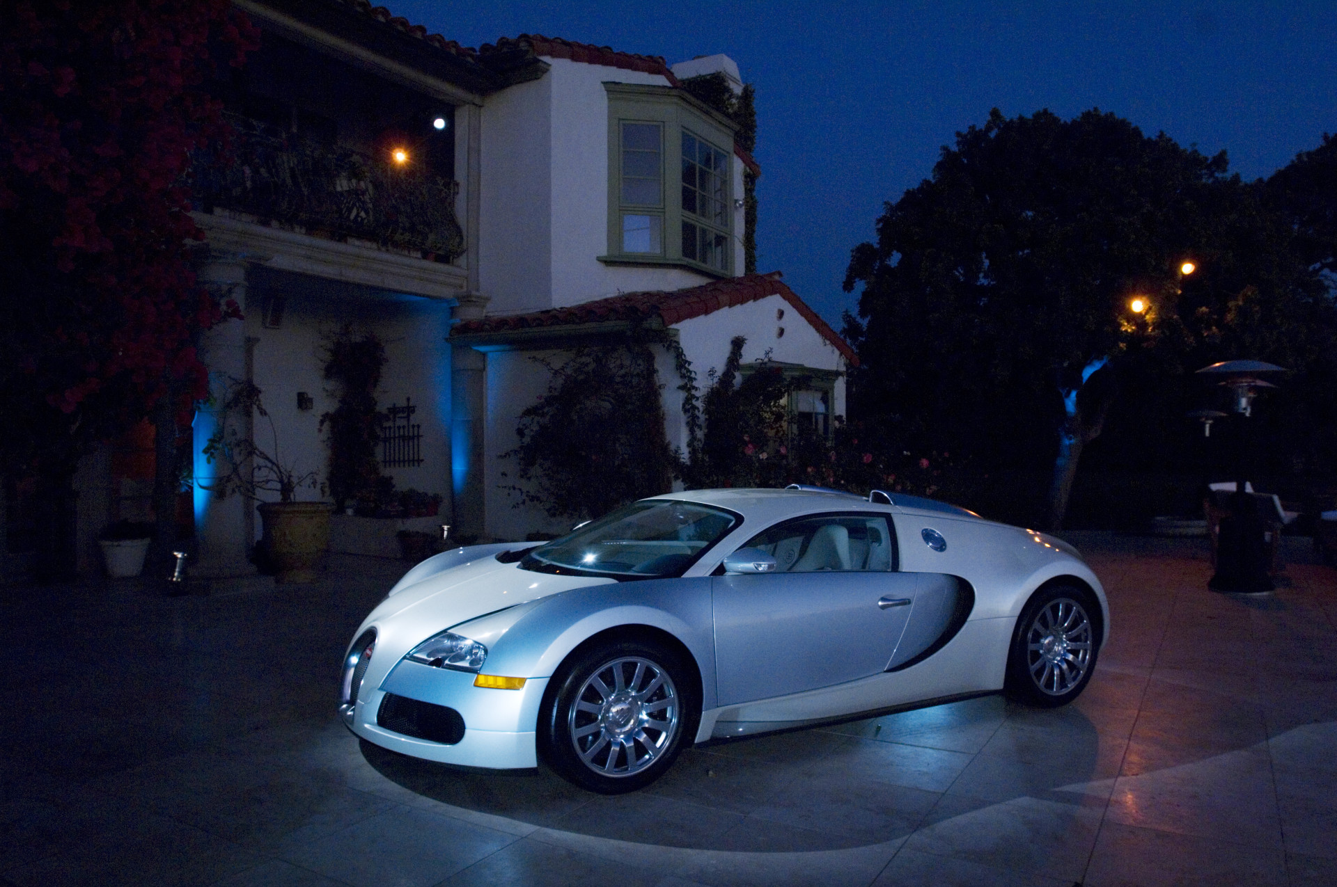 Bugatti Veyron arriving at an elegant private estate for an exclusive evening event featuring Mediterranean architecture and sophisticated event production.