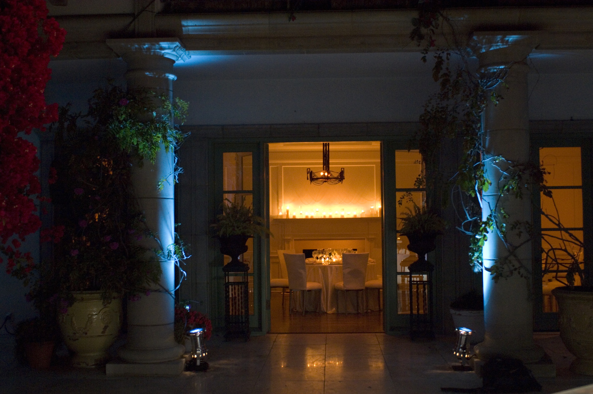 Grand entrance to a luxury private estate illuminated with architectural lighting, candlelit interiors, and elegant landscaping for an evening wedding or special event.