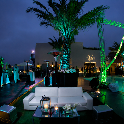 Luxury rooftop event produced by Gianna & Company featuring aerial performers above the pool, custom lighting, lounge seating, and elegant evening entertainment at a private estate.