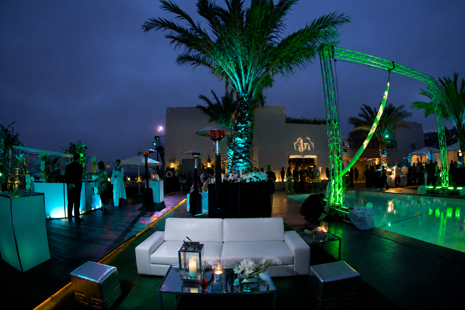 Luxury rooftop event produced by Gianna & Company featuring aerial performers above the pool, custom lighting, lounge seating, and elegant evening entertainment at a private estate.