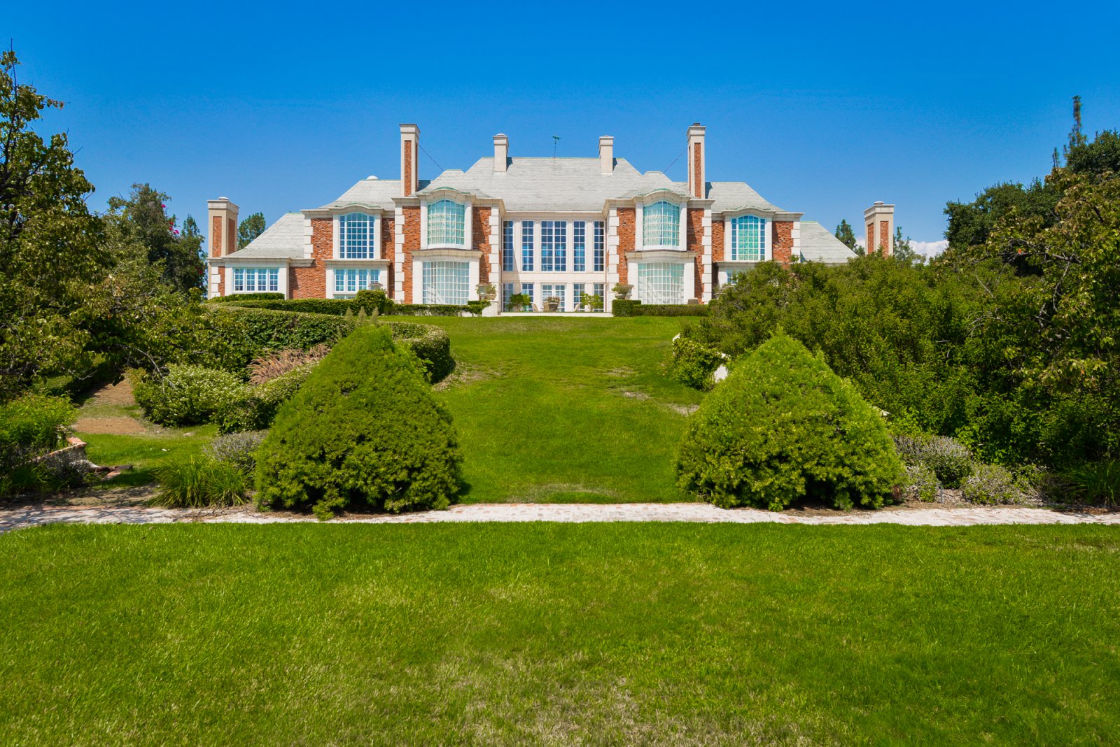 Front exterior of a classic Pasadena estate featuring timeless architecture, manicured gardens, and circular driveway.