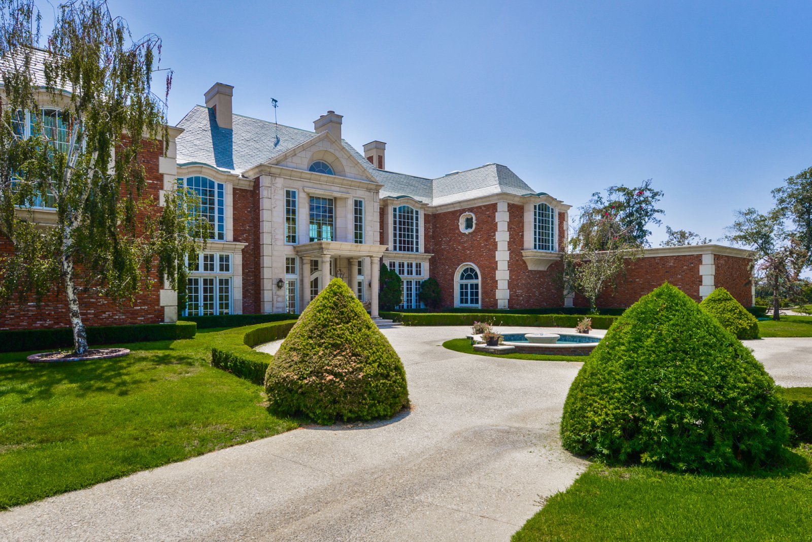 Elegant front courtyard with circular fountain and manicured landscaping at a classic Pasadena private estate.
