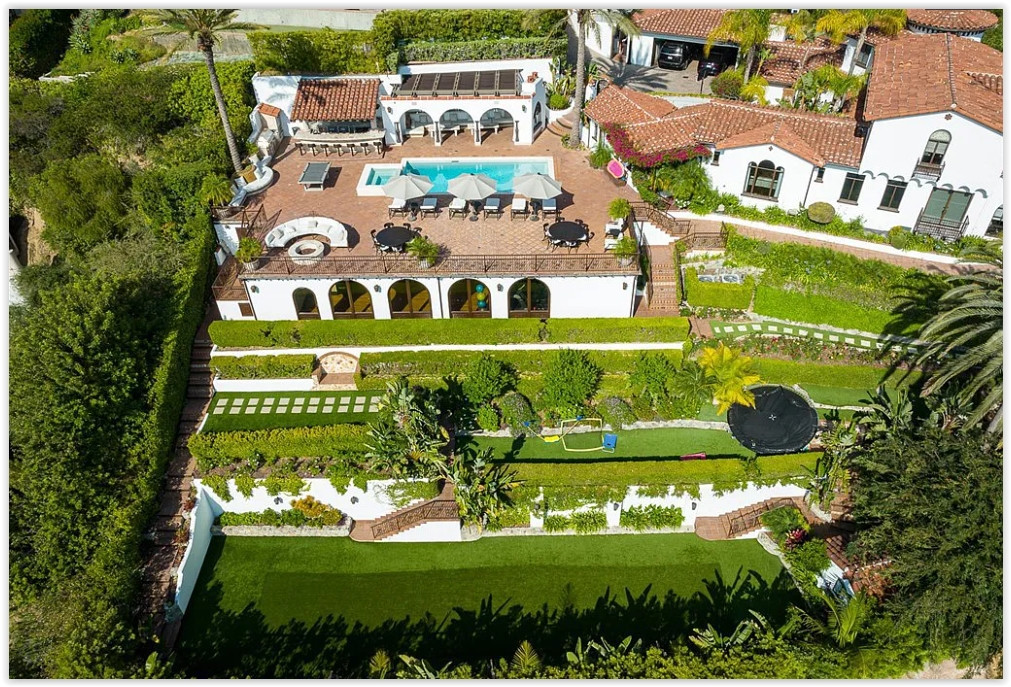 Aerial view of a luxury Spanish estate featuring terraced gardens, expansive lawns, pool, and outdoor entertaining areas.