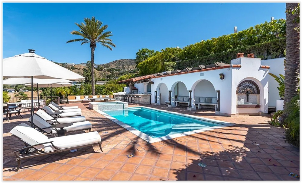 Resort-style pool terrace with covered outdoor lounge, Spanish arches, and elegant entertaining spaces.