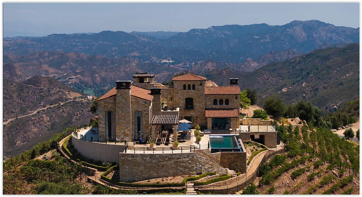 Stone-clad Malibu vineyard estate with expansive terraces and panoramic mountain views.