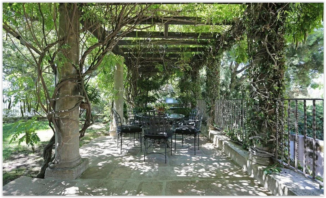 Shaded pergola with outdoor seating overlooking the gardens of a private Pasadena estate.