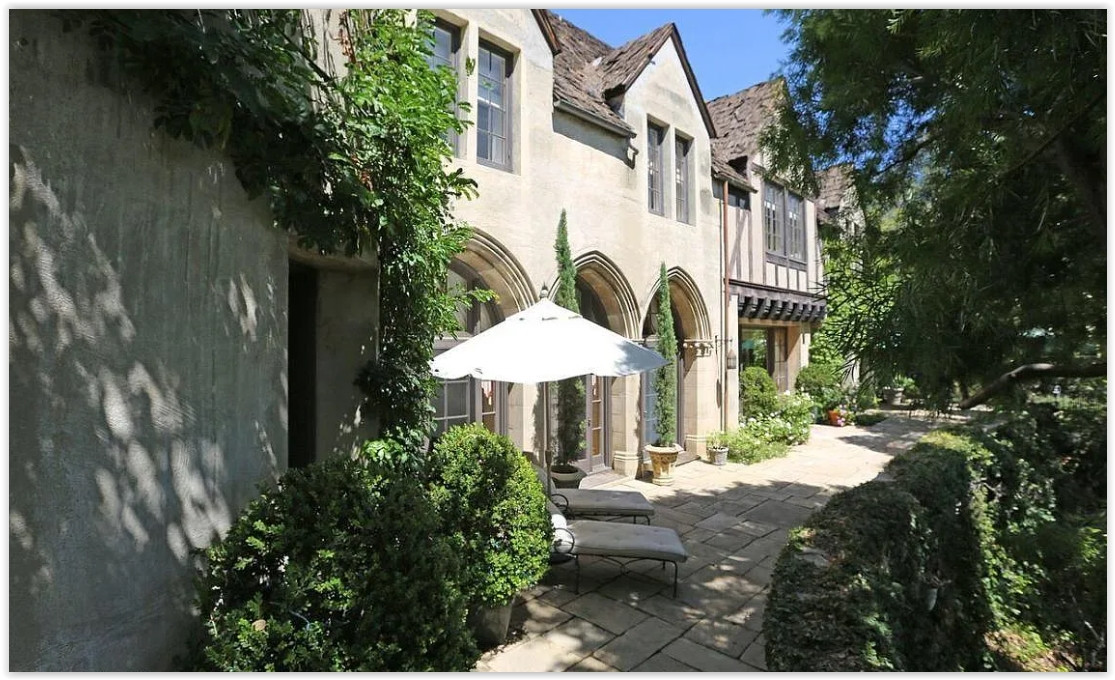 Stone garden terrace lined with ivy-covered architecture and mature landscaping at a private Pasadena estate.