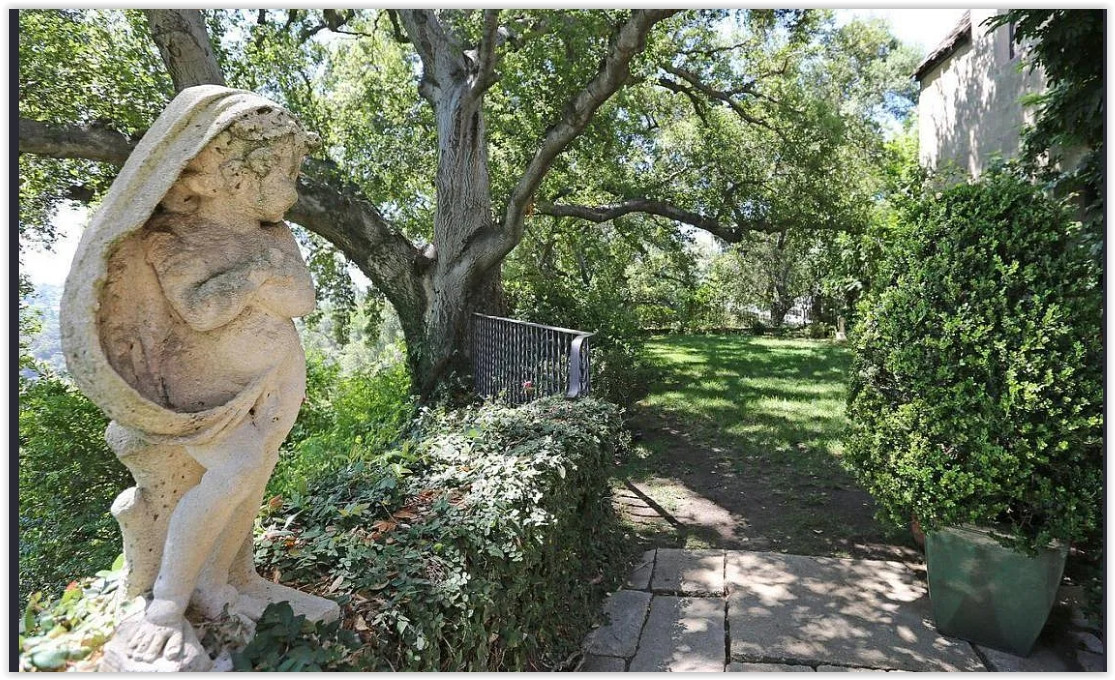 Garden pathway with mature oak trees and a classic stone statue at a private Pasadena estate.
