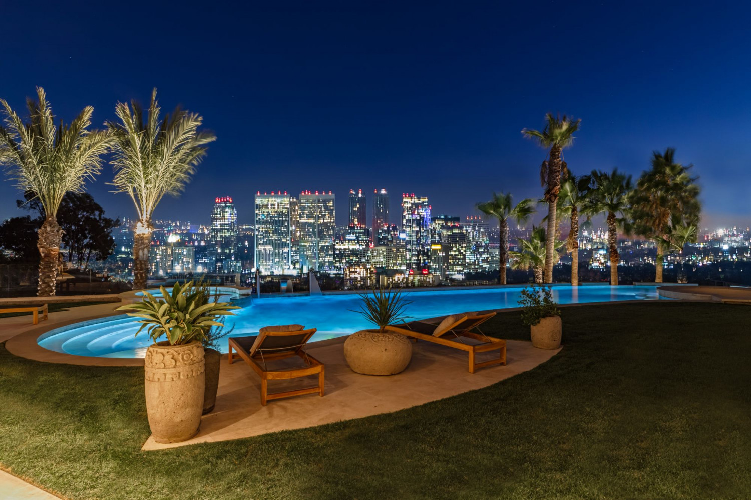 Contemporary Beverly Hills estate illuminated at twilight with a resort-style pool, elegant outdoor entertaining spaces, and striking modern architecture.
