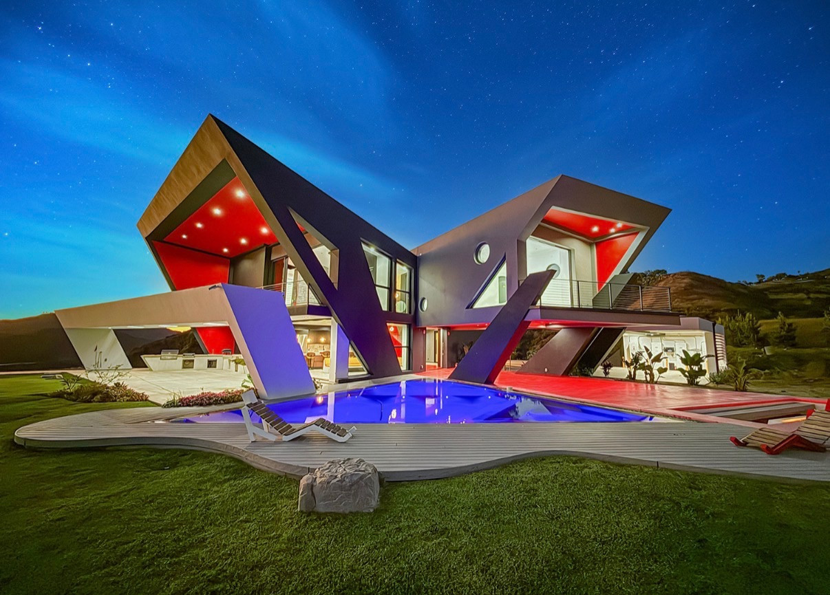 Distinctive modern Malibu retreat with dramatic angular architecture, illuminated pool, and sweeping hillside views at twilight.