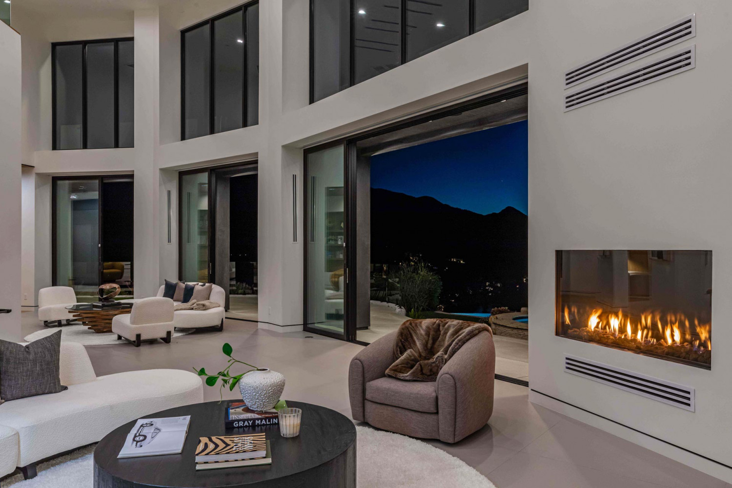 Modern living room with sculptural seating and floor-to-ceiling glass overlooking hillside canyon views in Agoura Hills estate.