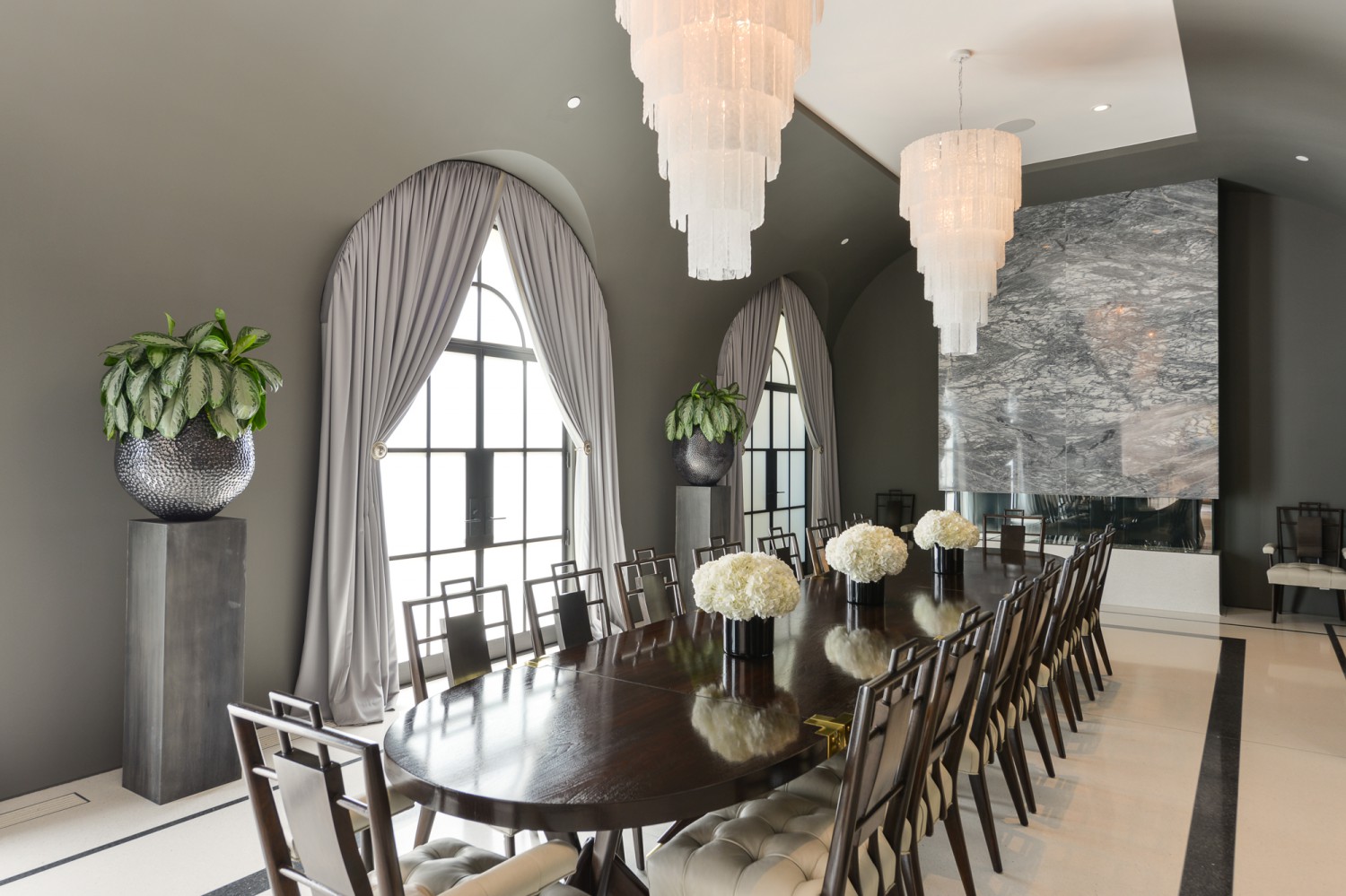 Formal dining room with arched windows, chandeliers and long table for elegant gatherings