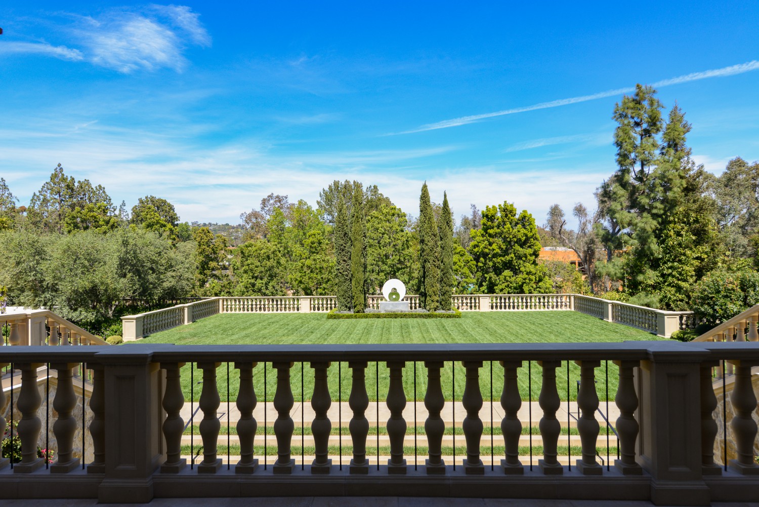 Expansive manicured lawn with formal balustrades, mature trees and landscaped garden views