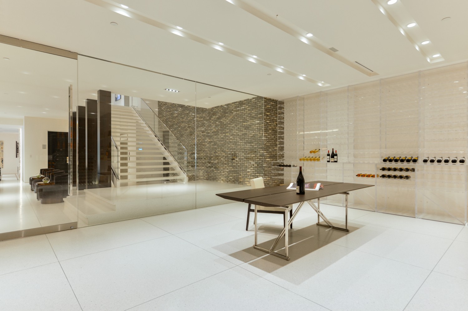 Glass-enclosed wine room with contemporary staircase and stone accent wall