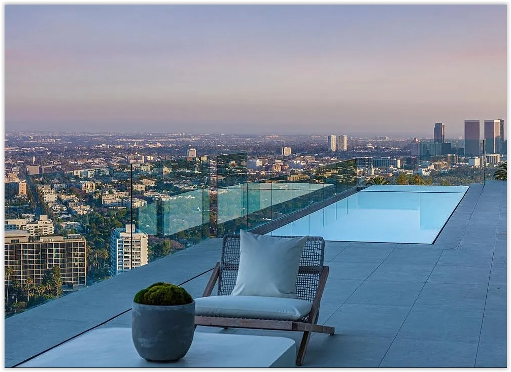 Infinity pool with chaise lounges overlooking the Los Angeles skyline from a modern hillside estate